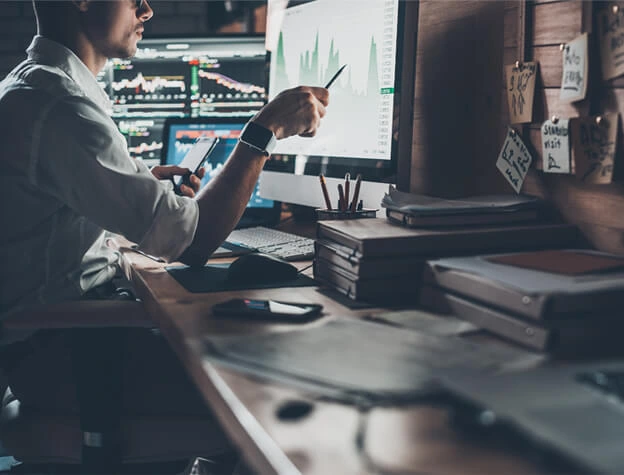 a man pointing to a graph on his monitor screen